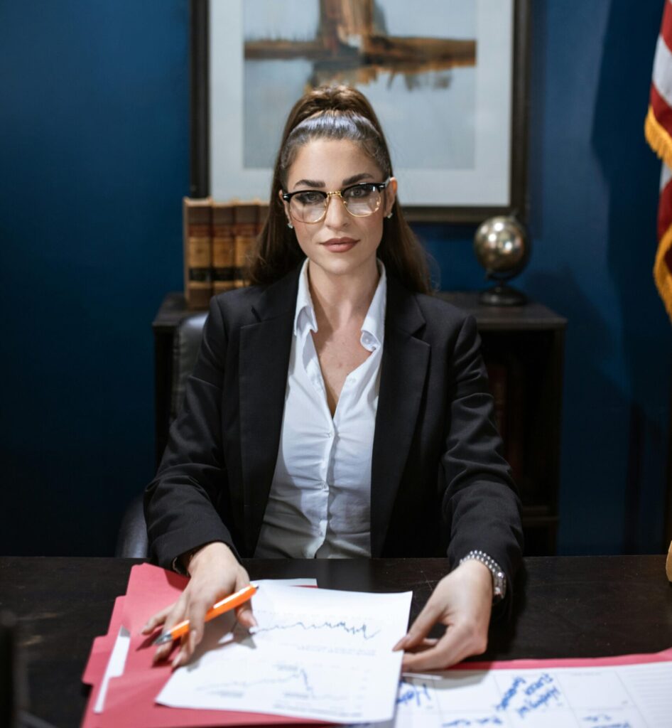 Businesswoman wearing a black blazer working at a desk with papers and charts.